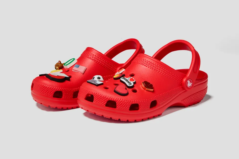 Pair of red Crocs × TEDxPortland classic clogs with Jibbitz charms, three-quarter view