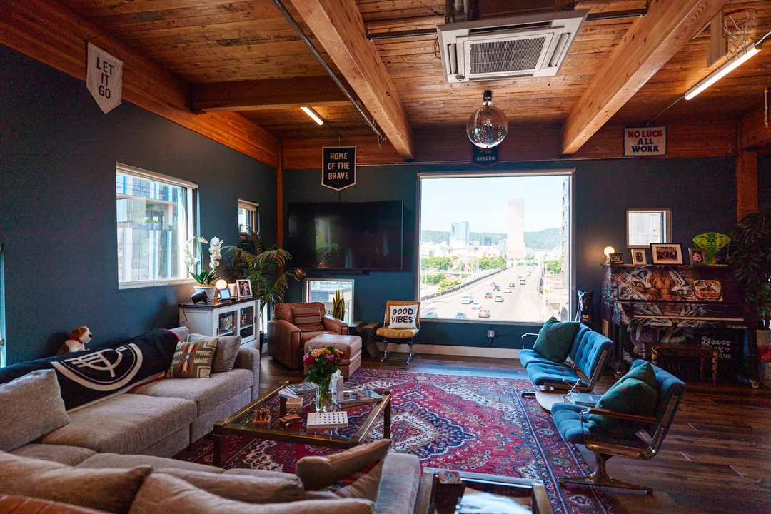 TEDxPortland HQ: sofa seating and armchairs around a rug, with a view of the city through the window