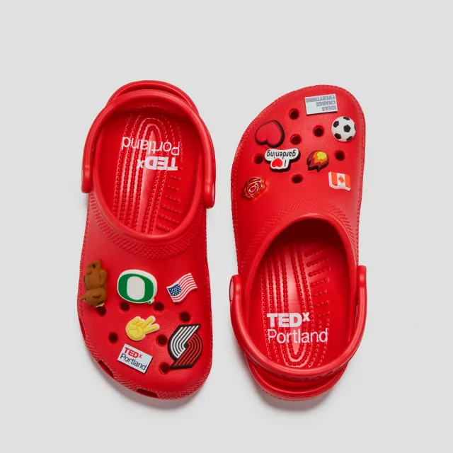 Pair of red Crocs × TEDxPortland classic clogs from above, decorated with Jibbitz charms